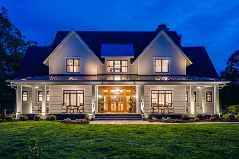 Custom farmhouse exterior lit up at dusk