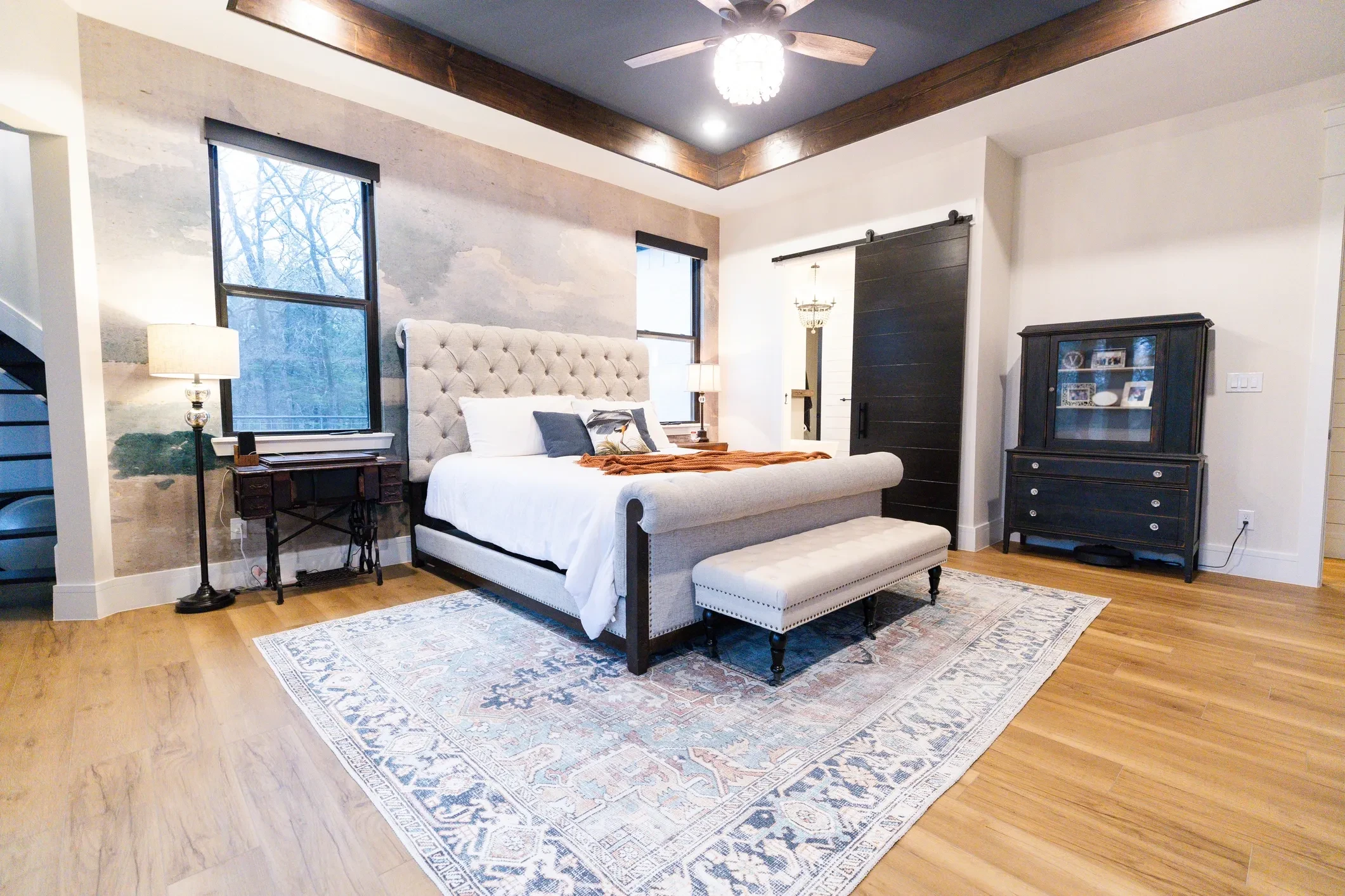 Custom barndominium master bedroom with barn door and wood beam ceiling